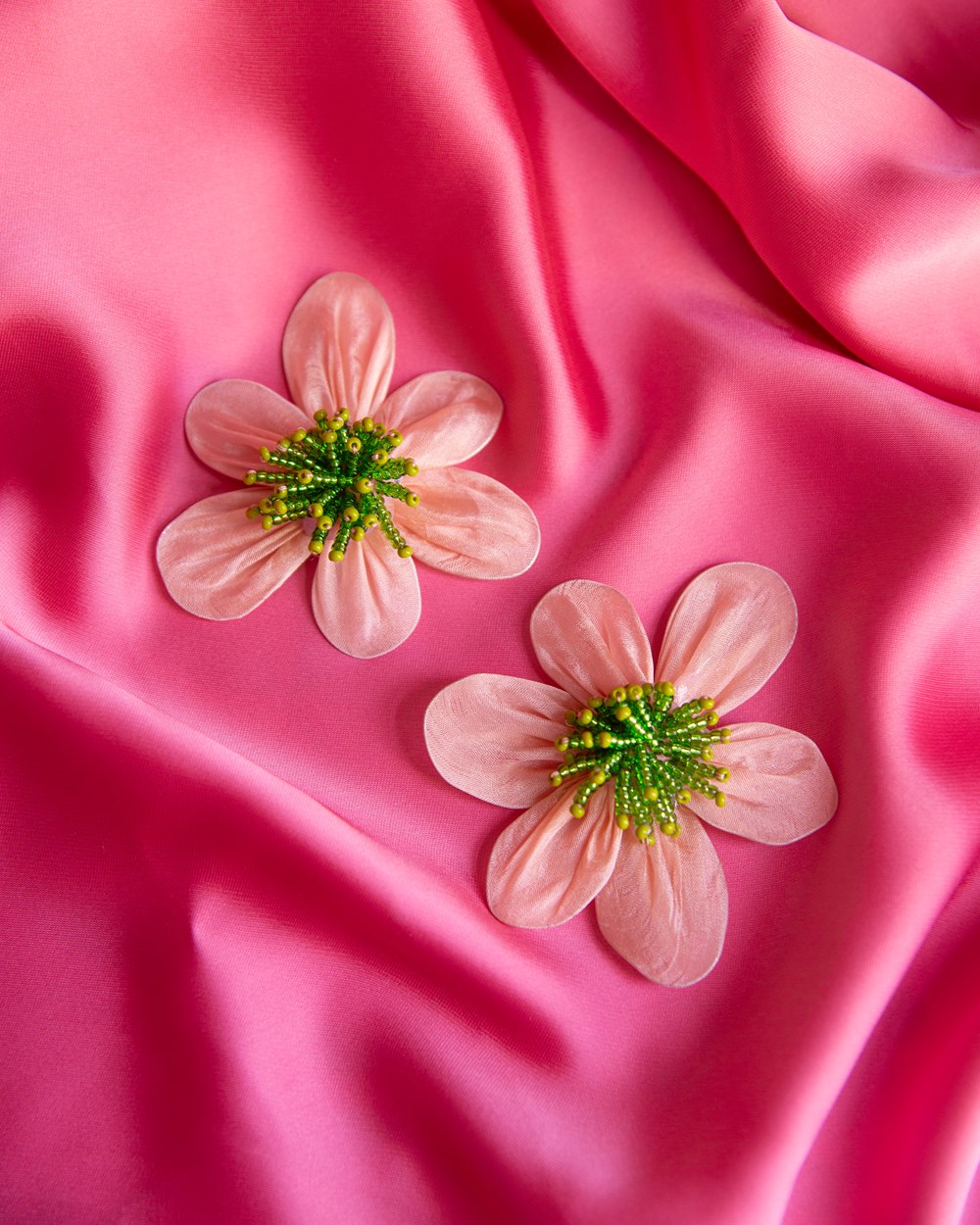 Foto av rosa blomster laget av perler og silke.