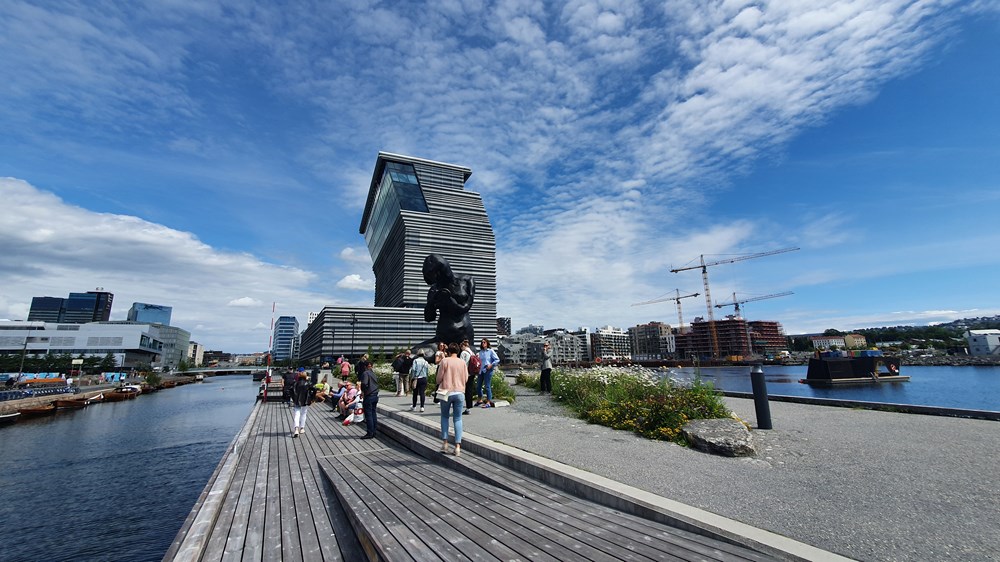 A wide shot of the museum, with the sculpture The Mother in front, a handfull of people standing by.